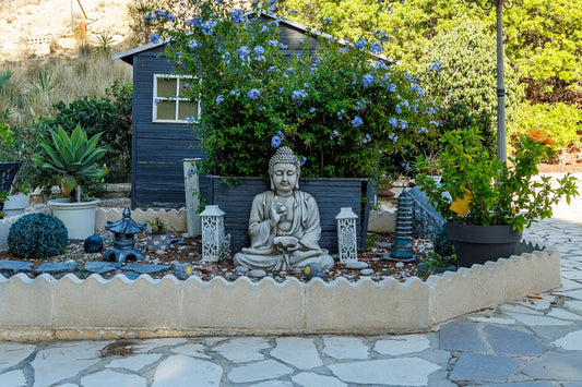 Buddha statue in a garden with a small shed.