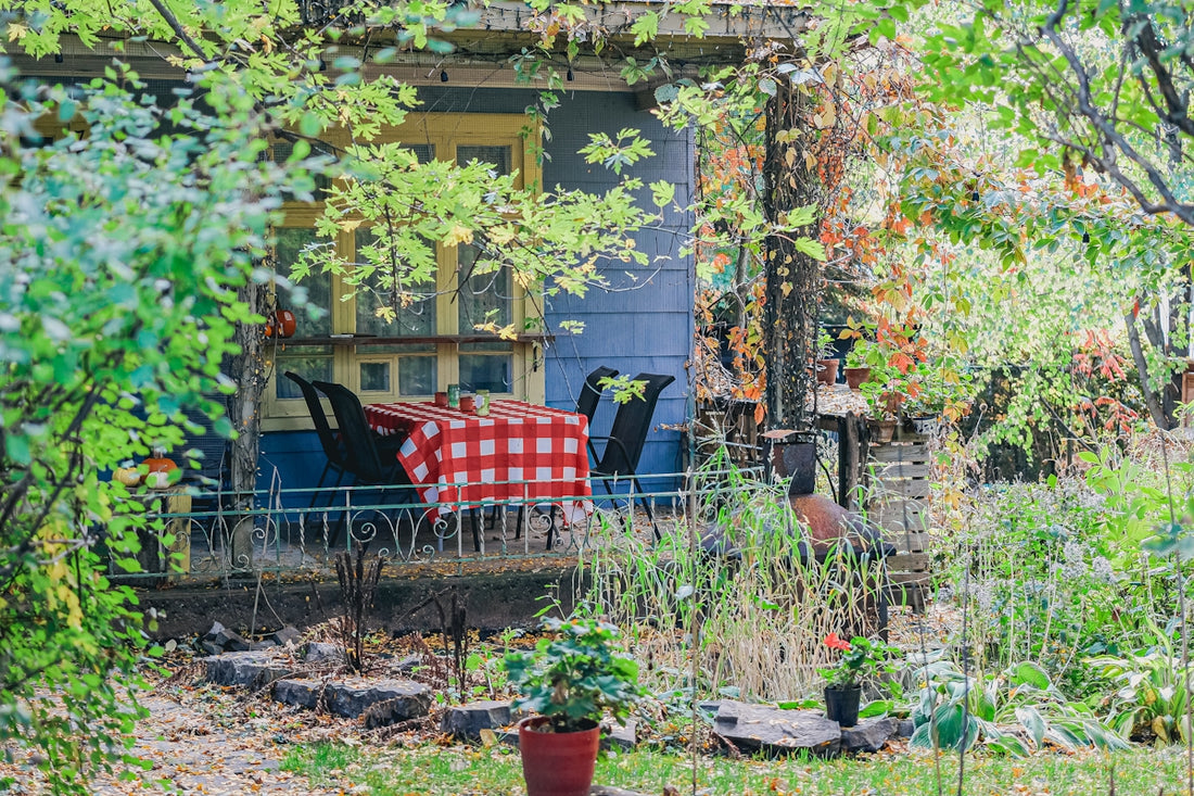 A porch with a checkered tablecloth and chairs.