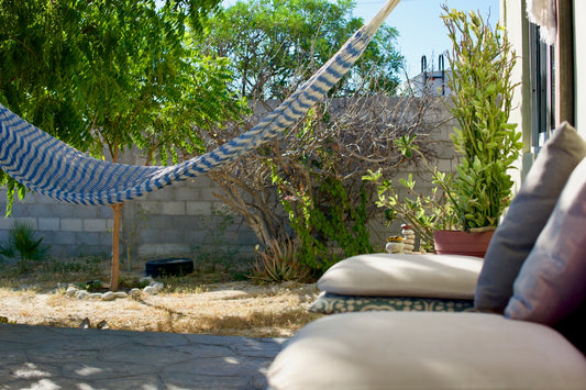 A hammock hangs in a sunny backyard with outdoor seating.